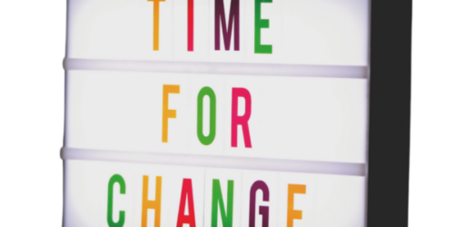Une boîte lumineuse affiche le message "TIME FOR CHANGE" avec des lettres colorées sur fond blanc.