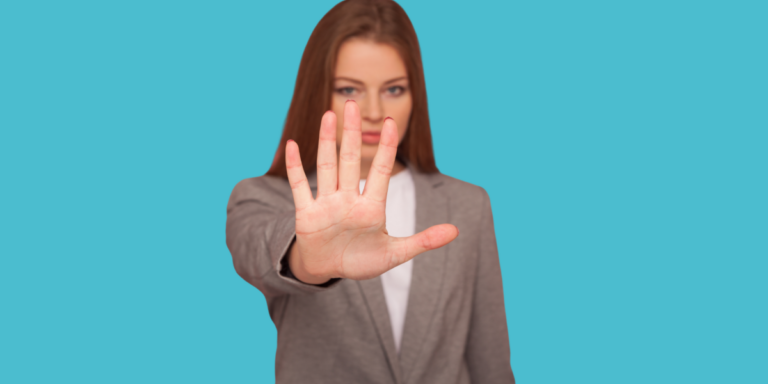 Une personne en costume gris tend la main vers l'avant, paume ouverte, sur un fond bleu uni.